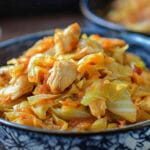 Fried chicken and cabbage served with carrots and parsley on a rustic table