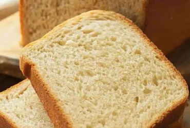 Low calorie bread recipe with sliced homemade bread on a wooden board.
